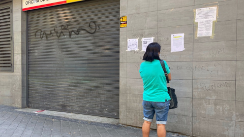 Una persona observa uno de los carteles con instrucciones para hacer trámites por internet colocados en la fachada de una oficina del SEPE. E.P./Eduardo Parra