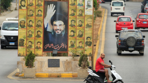 Un hombre monta una moto junto a un póster que representa al líder de Hezbolá, Sayyed Hassan Nasrallah, en laciudad libanesa de Sidón. REUTERS/Ali Hashisho