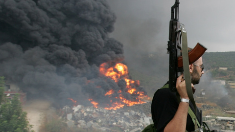 Un guerrillero libanés de Hezbolá mira un fuego que se eleva desde un objeto en llamas en un suburbio de Beiru, en julio de 2006, durante la guerra con Israel. REUTERS/Issam Kobeisi