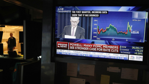 Un monitor de TV en el patio de negociación de la Bolsa de Nueva York en Wall Street muestra la rueda de prensa del presidente de la Reserva Federal, Jerome Powell, tras la reunión en la que se han mantenido sin tocar los tipos de interés. REUTERS/Luca