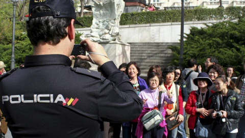 Un policía toma una foto a un grupo de turistas japoneses en Madrid.-EFE