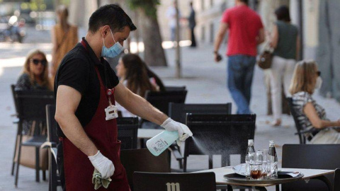 Un camarero desinfecta una mesa de una terraza / EFE