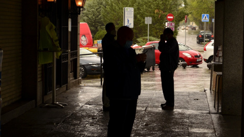 Los vecinos de El Pardo se refugian de la lluvia en unos soportales del centro. JOSE CARMONA.