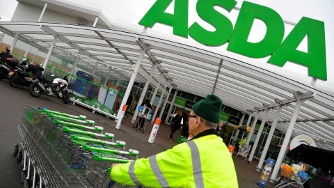 Un trabajador traslada una fila de carritos de la compra en un establecimiento de la cadena de supermercados británica Asda, en Londres. REUTERS/Toby Melville