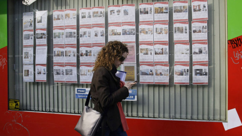 Una joven pasa por delante de una inmobiliaria con anuncios de casas en alquiler o en venta en el centro de Madrid. REUTERS/Andrea Comas