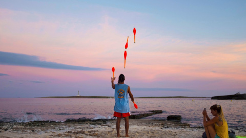 Una hombre realiza malabares al atardecer en la playa de Punta Prima en Menorca, Baleares, este miércoles. EFE/ David Arquimbau Sintes