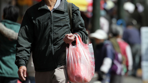 Un hombre carga una bolsa de plástico con la compra. AFP