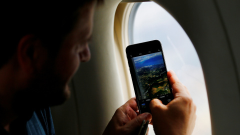 Un hombre toma una fotografía desde la ventalla de su asiento en un viaje en avión. REUTERS/Denis Balibouse