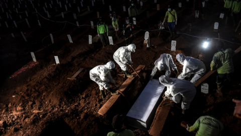 Trabajadores con trajes protectores entierran a una víctima de la enfermedad por coronavirus en Indonesia. Antara Foto / Muhammad Adimaja / REUTERS