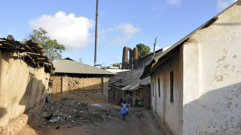 Una niña camina por las calles del poblado chabolista de Owino Uhuru, en Mombasa (Kenia), cuyos habitantes han demandado al Gobierno por permitir la actividad de una fábrica ilegal levantada entre sus viviendas (al fondo) que emitía vertidos de plomo.-