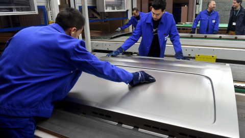 Varios trabajadores preparan una purta corredera para un automóvil en el Centro de Innovación del fabricante de componentes de automóvil Gestamp, en la localidad alemana de  in Bielefeld. AFP/Patrick Stollarz