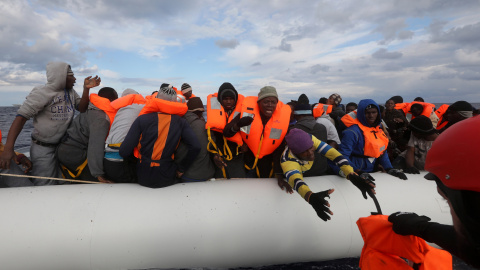 Un voluntario de Proactiva Open Arms acerca un achaleco salvavidas a los inmigrantes que tratan de rescatar en el Mediterráneo.-REUTERS/Yannis Behrakis