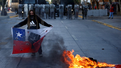 Una manifestante sostiene un a bandera de Chile frente a un contingente de Fuerzas Especiales de Carabineros durante una protesta en la Plaza Italia de Santiago. EFE/Alberto Valdés