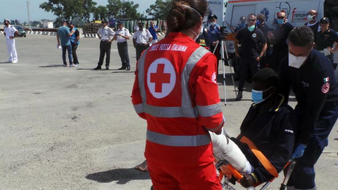 Trabajadores de la Cruz Roja ayudan a desembarcar a los 402 inmigrantes rescatados en el Mediterraáneo a su llegada al puerto de Brindisi (Italia). /EFE