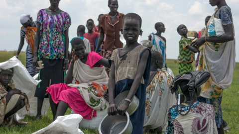 Mujeres y niños desplazados esperan una ración de comida proporcionada por el Programa Mundial de Alimentos. - AFP