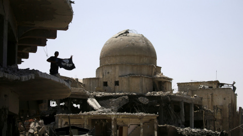 Un miembro de las fuerzas iraquíes levanta una bandera del Estado Islámico sobre un edificio destruido en la batalla en Mosul REUTERS/Thaier Al-Sudani