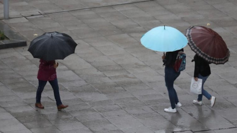 Escolares se protegen de la lluvia con paraguas en Bilbao / EFE