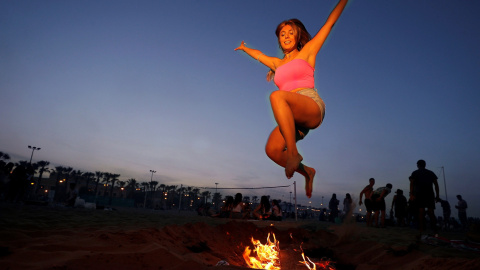 Una mujer salta sobre una hoguera para celebrar la noche de San Juan en la playa La Malvarrosa en València | EFE