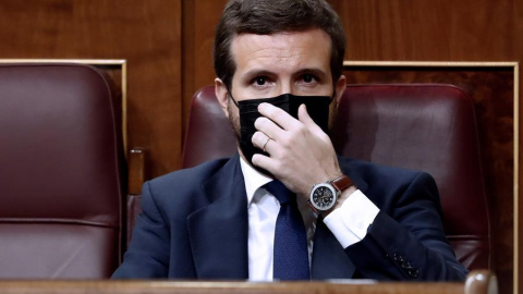 El líder del Partido Popular, Pablo Casado, se coloca la mascarilla mientras asisten a la moción de censura presentada por Vox al gobierno de coalición en el Congreso de los Diputados este miércoles. EFE/Mariscal