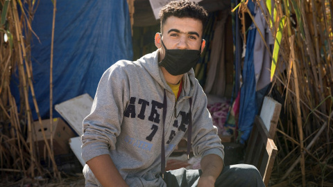 Ahmed vive en una chabola con tres colchones, construida entre cañas junto al cauce seco y lleno de basura que pasa al lado del CETI de Melilla.- EFE/Jesús Blasco de Avellaneda