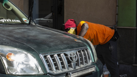 Un migrante lava un 4x4 por tres euros junto a la plaza de toros de Melilla, reconvertido en un CETI por saturación del centro durante la pandemia.- JAIRO VARGAS