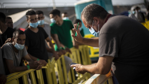 Un voluntario de Cruz Roja llama a los migrantes que podrán salir del puerto de Arguineguín, en Gran Canaria, tras varios días de espera.- JAIRO VARGAS