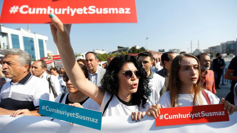 Varias presonas muestran el lema "Cumhuriyet no se silencia" durante una concentración delante del Palacio de Justicia de Estambul (Turquía) hoy, 24 de julio de 2017. Empleados del diario se sientan en el banquillo de los acusados hoy acusados de colabo