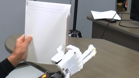 El sujeto amputado sostiene un cuaderno usando la prÃ³tesis de mano mioelÃ©ctrica con control de sinergia muscular