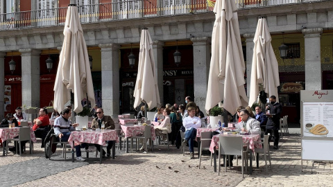 Varios turistas en su mayoría franceses disfrutan del sol en la Plaza Mayor de Madrid.