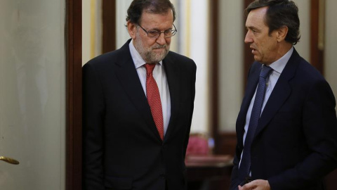 El presidente del Gobierno, Mariano Rajoy (i), conversa con el portavoz del PP en el Congreso, Rafael Hernando, en los pasillos de la Cámara Baja. /EFE