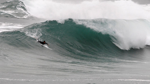 Un surfista practica surf en las grandes olas formadas en la playa de Ponzos de Ferrol.