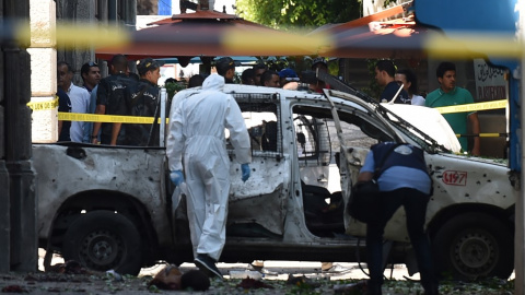 Dos investigadores analizan uno de los vehículos que ha hecho explosión este jueves en la capital de Túnez. /AFP