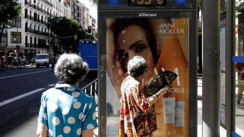 26/6/2019.- Dos mujeres que esperan la llegada del autobús observan los 35 grados que marca el termómetro de la marquesina a mediodía de hoy. La ola de calor, que comienza este miércoles, y que se prevé muy adversa por su intensidad, duración y exte