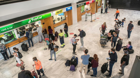 Varios turistas hacen cola ante una oficina de alquiler de vehículos a su llegada al aeropuerto César Manrique de Lanzarote.