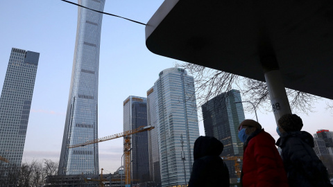 Varias personas en una parada de autobús, frente a los rascacielos del distrito financiero de Pekín. REUTERS/Tingshu Wang