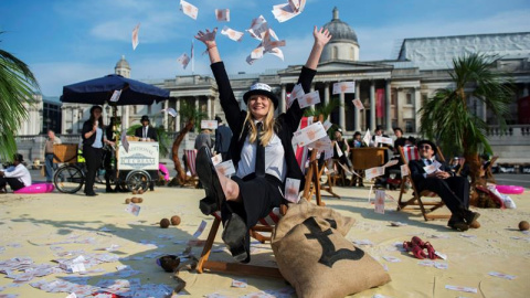 Una mujer lanza billetes al aire en una protesta contra los paraísos fiscales en la plaza Trafalgar de Londres. EFE/Hannah Mckay