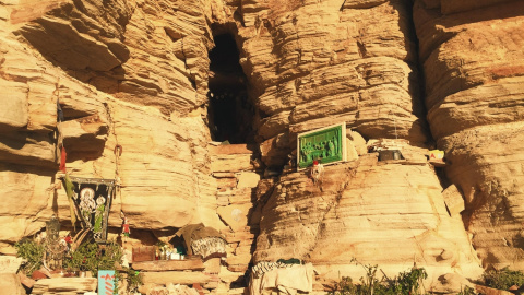 Entrada a la cueva adornada con plantas, escritos y otros elementos. - Mila García Nogales