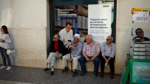 Un grupo de pensionistas sentados en la ventada de una sucursal del banco BBVA en Málaga.