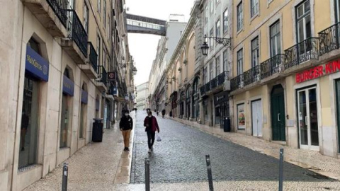 os personas caminan este miércoles por una calle vacía del centro de Lisboa (Portugal).