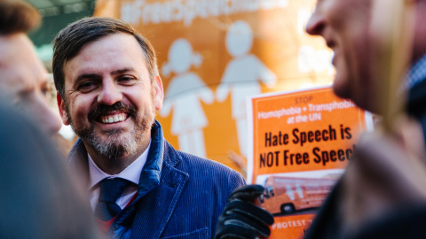 Ignacio Arsuaga, el presidente de "Hazte Oír", habla con los medios mientras un grupo de personas protestan por la presencia del 'Autobús del Odio' en Nueva York. EFE/Alba Vigaray