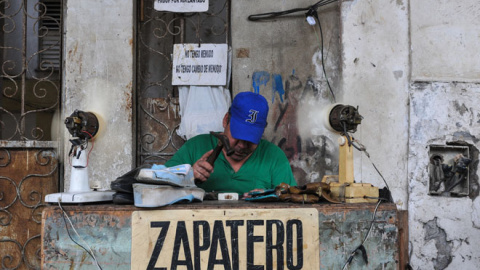 Un zapatero privado trabaja en la calle en La Habana /AFP (Yamil LAGE)