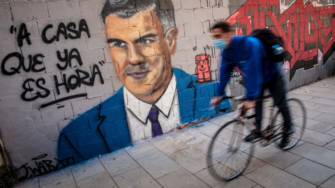 VALENCIA, 26/10/2020.Una persona en bicicleta pasa frente a una pintura mural del artista urbano J.Warx donde aparece el presidente del Gobierno, Pedro Sánchez, bajo la frase “A casa que ya es hora".