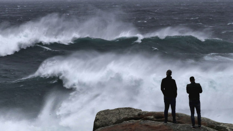 Unos turistas observan el oleaje en Muxía donde los fuertes vientos y lluvias anticipan la llegada de marejada del Atlántico en toda la cornisa cantábrica.