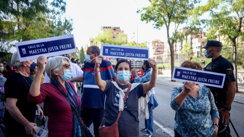 Tres mujeres muestran pancartas en las que figura una placa para la Calle Maestra Justa Freire, en una manifestación para que su nombre vuelva a la que hoy es la calle General Millán-Astray.