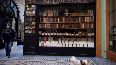 Una mujer y su perro frente a una librería en París.