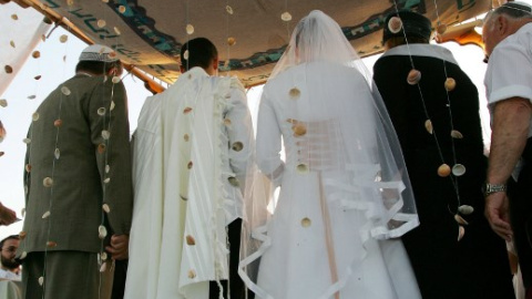 Pareja israelí bajo un altar judío durante su ceremonia de boda en el asentamiento de Neve Dekalim en la Franja de Gaza meridional. AFP PHOTO / DAVID FURST