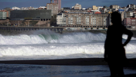 Una mujer observa las olas desde el paseo marítimo de A Coruña.