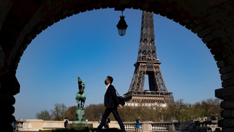 31/03/2021. Un peatón con mascarilla anda por el puente Bir Hakeim cerca de la Torre Eiffel poco antes de que Macron anunciara las nuevas restricciones, este miércoles en París. - EFE