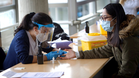 Una estudiante de Enfermería (i) realiza un test rápido de SARS-CoV-2