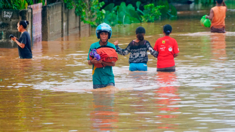 04/04/2021. Un hombre con casco lleva consigo sus pertenencias en un área afectada por las fuertes inundaciones en Indonesia y Timor Oriental. - Reuters